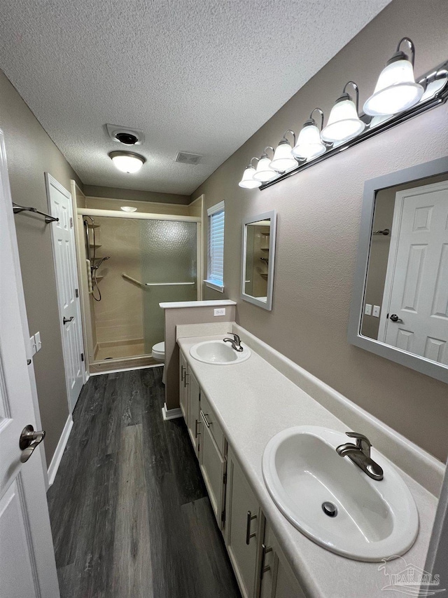 full bath featuring wood finished floors, a stall shower, a sink, and toilet