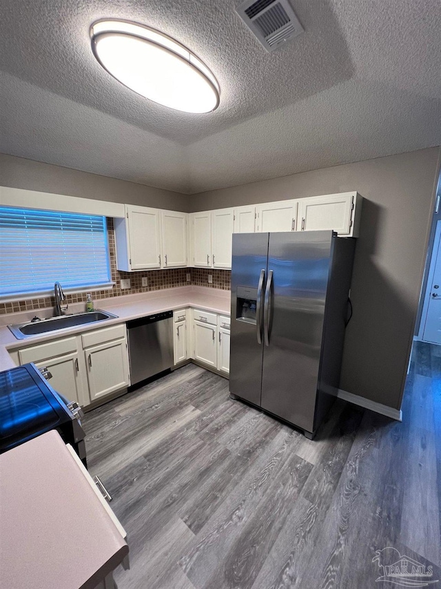 kitchen with stainless steel appliances, visible vents, a sink, and wood finished floors