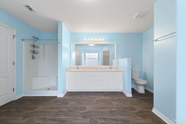 bathroom with toilet, a shower, a textured ceiling, vanity, and hardwood / wood-style flooring