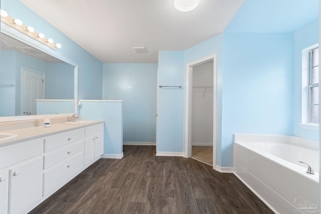 bathroom with vanity, hardwood / wood-style flooring, a textured ceiling, and a bathing tub