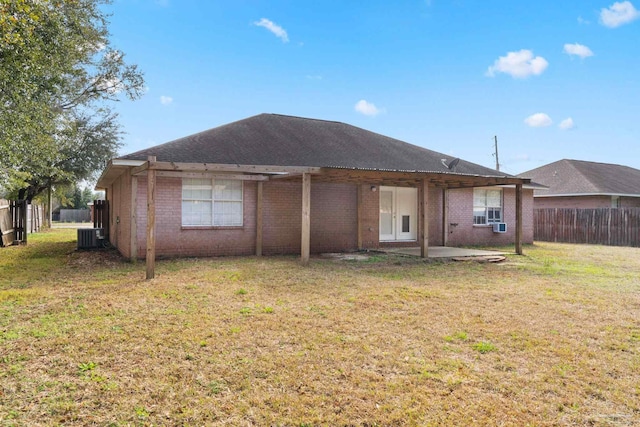 rear view of house with cooling unit, a patio area, and a lawn