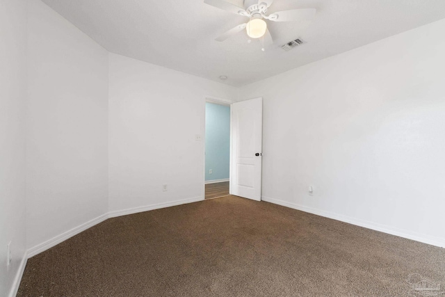 empty room with ceiling fan and dark colored carpet