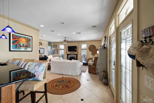 living room featuring ceiling fan, light tile patterned floors, and ornamental molding