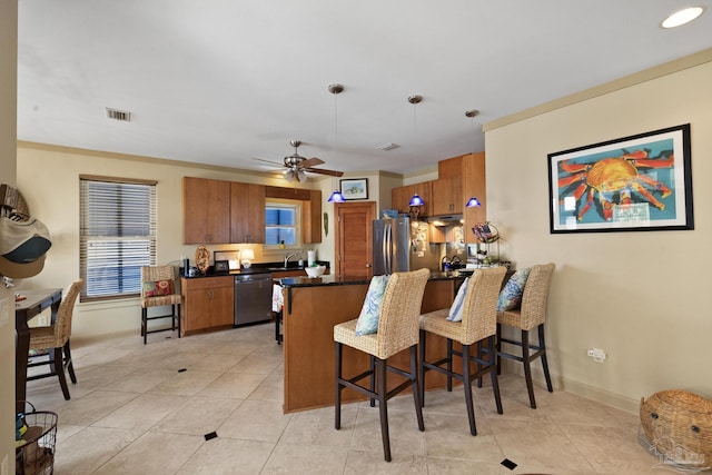 kitchen featuring appliances with stainless steel finishes, decorative light fixtures, ornamental molding, a breakfast bar, and sink