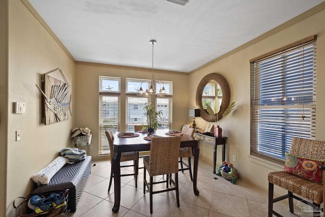 dining area featuring ornamental molding, a chandelier, and light tile patterned flooring