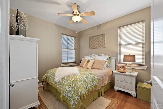 bedroom featuring ceiling fan, hardwood / wood-style flooring, and multiple windows