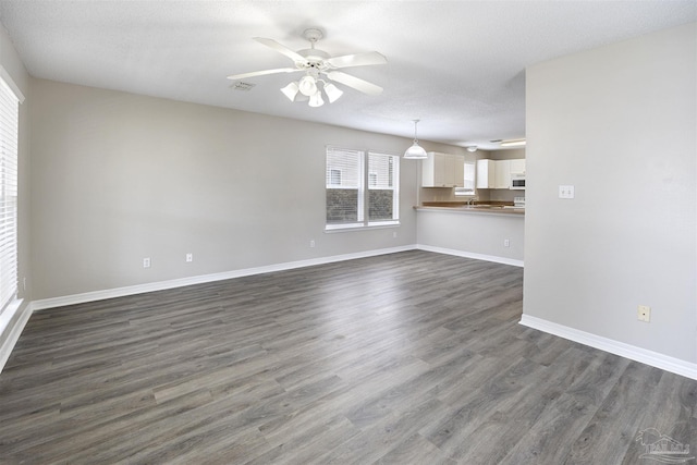 32 Enchanted Way, Santa Rosa Beach, FL 32459 - unfurnished living room featuring dark wood-style flooring, baseboards, and a ceiling fan