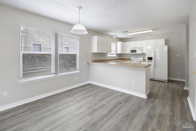 32 Enchanted Way, Santa Rosa Beach, FL 32459 - kitchen featuring white appliances, a sink, a textured ceiling, wood finished floors, and a peninsula