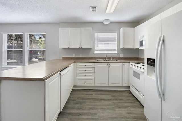 32 Enchanted Way, Santa Rosa Beach, FL 32459 - kitchen with white appliances, a sink, a peninsula, dark countertops, and a textured ceiling