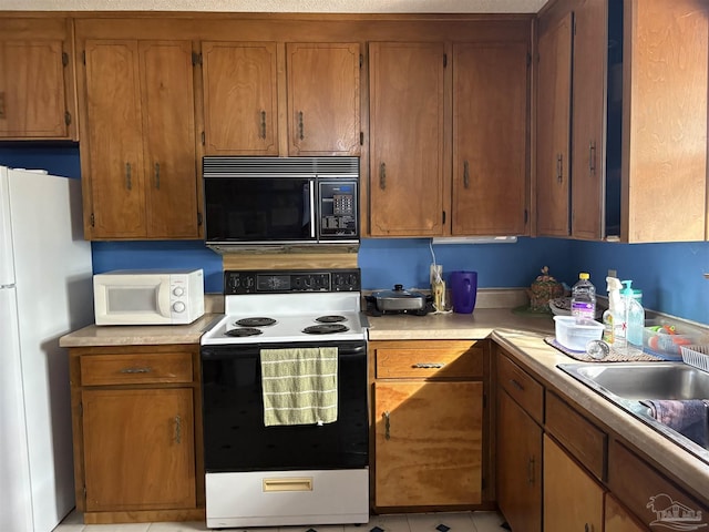 kitchen with sink, white appliances, and light tile patterned floors