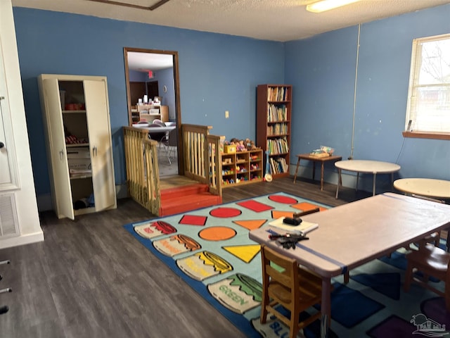 playroom with dark hardwood / wood-style floors and a textured ceiling