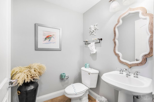 bathroom featuring toilet, a sink, and baseboards