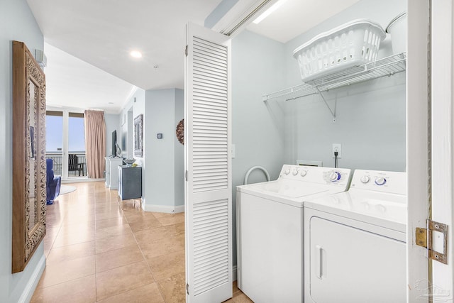 laundry room featuring laundry area, washer and clothes dryer, baseboards, and light tile patterned floors