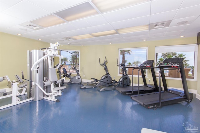 workout area with a healthy amount of sunlight, baseboards, visible vents, and a paneled ceiling