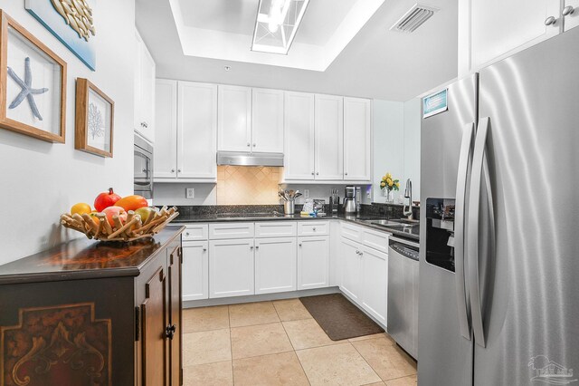 kitchen featuring visible vents, appliances with stainless steel finishes, white cabinets, a sink, and under cabinet range hood