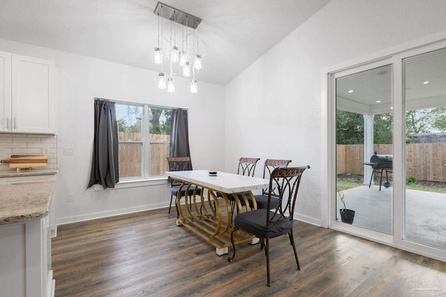 dining space featuring dark wood finished floors, an inviting chandelier, and baseboards