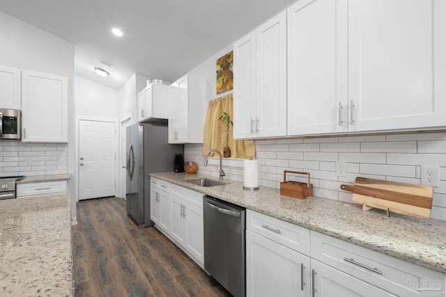 kitchen with white cabinetry, stainless steel appliances, lofted ceiling, and a sink