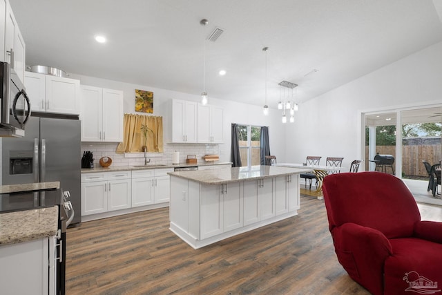 kitchen with a healthy amount of sunlight, visible vents, a sink, vaulted ceiling, and white cabinets