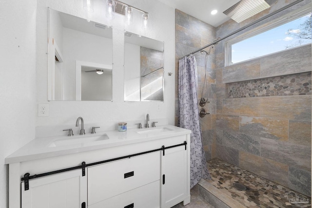 full bath with double vanity, tiled shower, and a sink