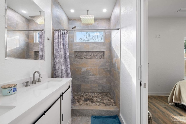 bathroom featuring visible vents, a sink, wood finished floors, a shower stall, and double vanity