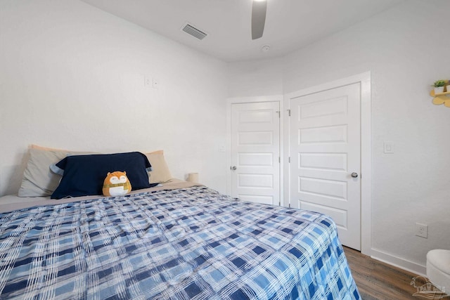 bedroom with baseboards, wood finished floors, visible vents, and ceiling fan