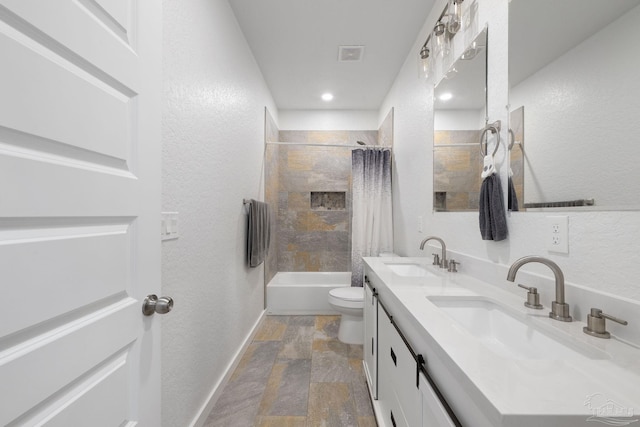 bathroom featuring double vanity, toilet, visible vents, and a sink