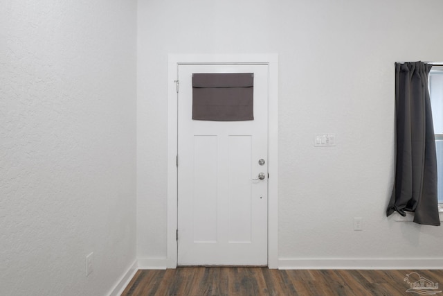 foyer entrance featuring baseboards and dark wood-style flooring