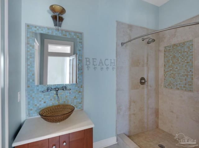 bathroom featuring vanity, backsplash, and tiled shower