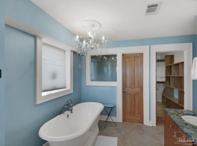 bathroom with an inviting chandelier, a tub to relax in, and vanity