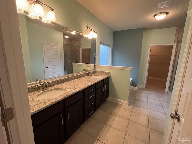 bathroom featuring tile patterned flooring, vanity, a textured ceiling, and walk in shower