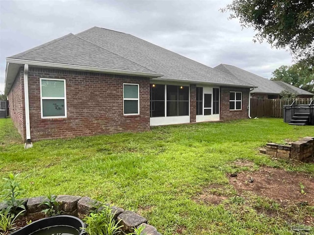 rear view of house featuring a sunroom, cooling unit, and a lawn