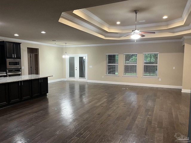 unfurnished living room featuring a raised ceiling, crown molding, dark wood-type flooring, and ceiling fan