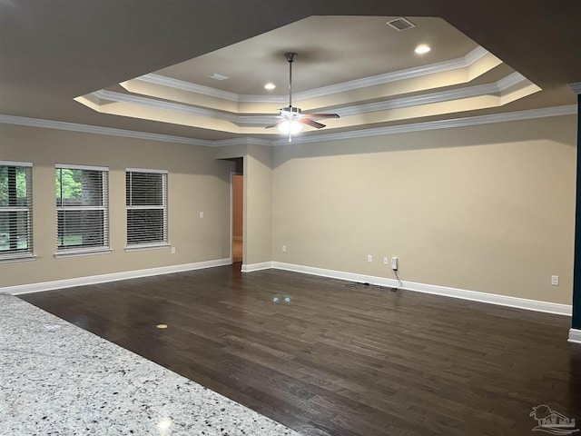 spare room featuring a tray ceiling, dark wood-type flooring, and ornamental molding