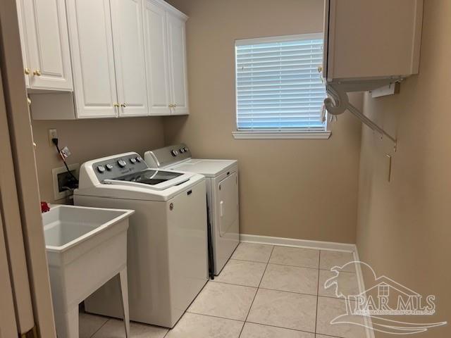 clothes washing area with cabinets, light tile patterned flooring, separate washer and dryer, and sink