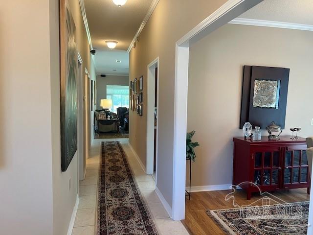 hall with ornamental molding and light hardwood / wood-style flooring