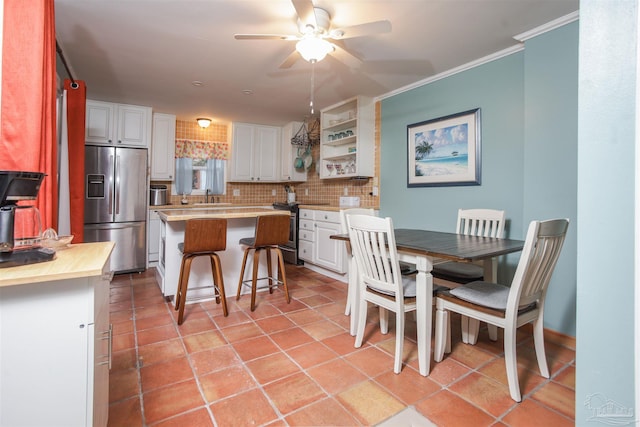 kitchen featuring decorative backsplash, appliances with stainless steel finishes, a breakfast bar, white cabinets, and a center island