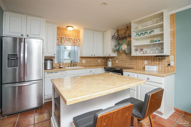 kitchen featuring stainless steel fridge, a breakfast bar, sink, black electric range, and white cabinetry