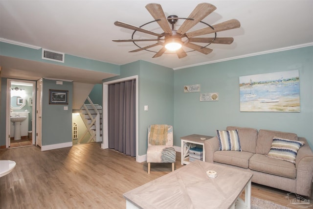 living room featuring light wood-type flooring, ceiling fan, ornamental molding, and sink