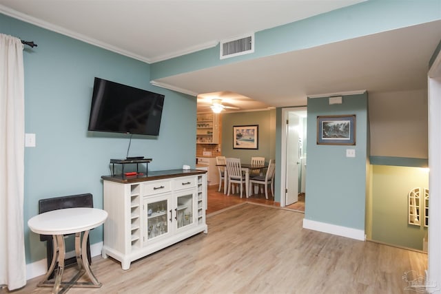 living room featuring light hardwood / wood-style floors, ceiling fan, and crown molding