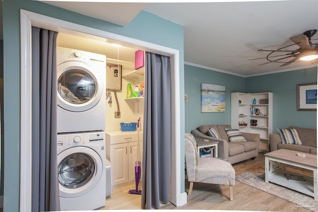 laundry area with light wood-type flooring, stacked washing maching and dryer, ceiling fan, and crown molding