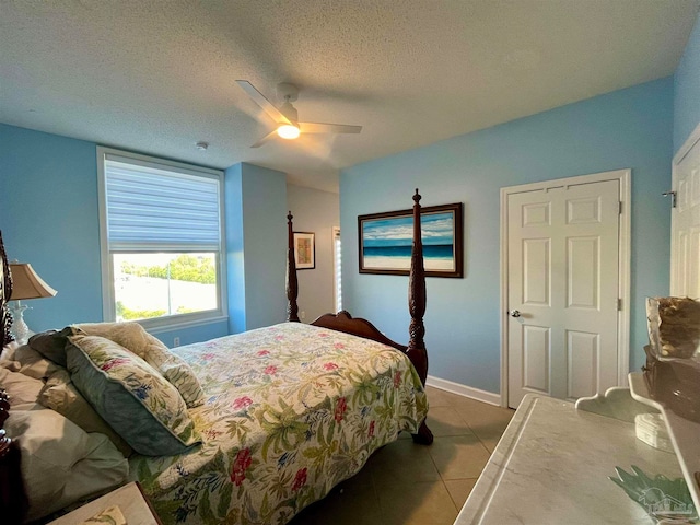 bedroom with ceiling fan, a textured ceiling, and light tile patterned floors