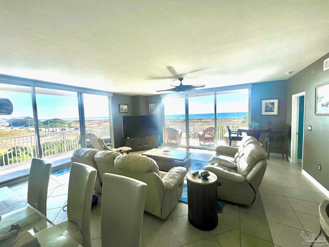 living room featuring expansive windows, a textured ceiling, ceiling fan, and light tile patterned floors