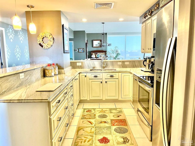 kitchen with appliances with stainless steel finishes, kitchen peninsula, decorative light fixtures, and light stone counters