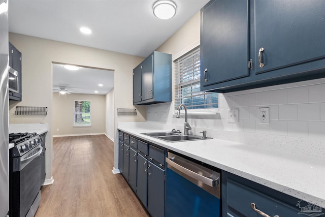 1010 W Lloyd St, Pensacola, FL 32501 - kitchen with dishwashing machine, stainless steel gas stove, a sink, blue cabinetry, and light wood-style floors
