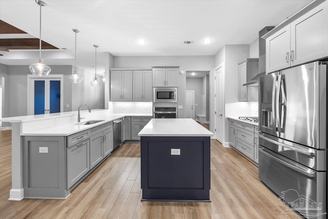 kitchen featuring pendant lighting, a center island, stainless steel appliances, and gray cabinets