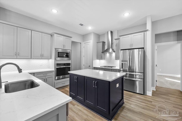 kitchen with decorative backsplash, appliances with stainless steel finishes, light stone countertops, wall chimney exhaust hood, and sink