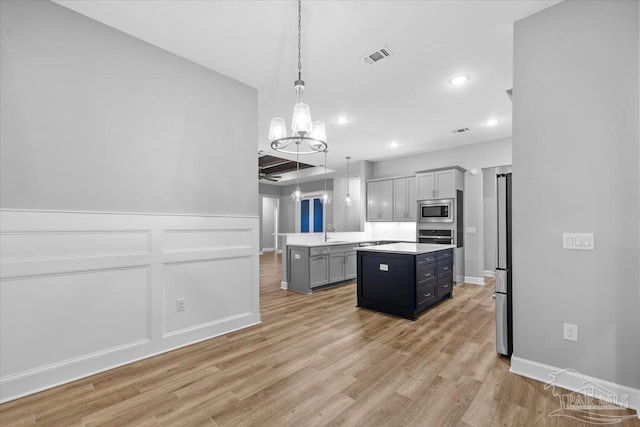 kitchen featuring gray cabinetry, sink, stainless steel appliances, pendant lighting, and a kitchen island