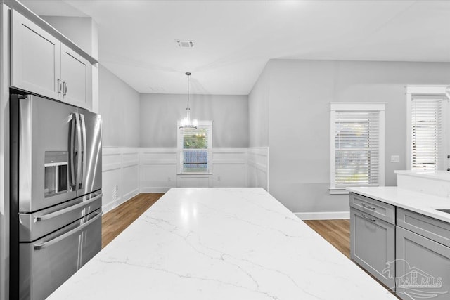 kitchen featuring light stone countertops, stainless steel fridge with ice dispenser, dark hardwood / wood-style flooring, and pendant lighting