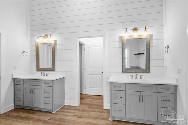 bathroom with wood-type flooring, vanity, and wood walls