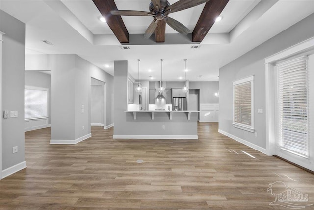 unfurnished living room with beamed ceiling, light hardwood / wood-style floors, and ceiling fan